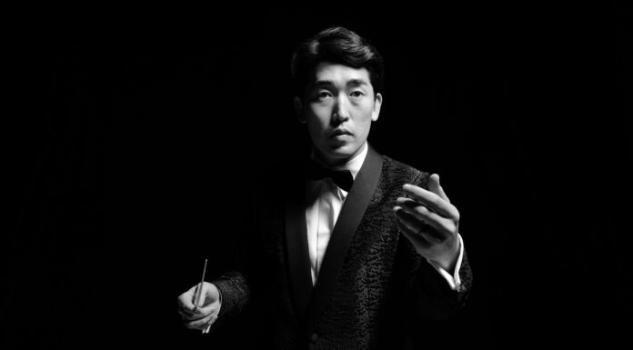 Internationally renowned conductor returns to Macon for homecoming concert A man in a formal suit holds a conducting baton and raises the other hand in direction.