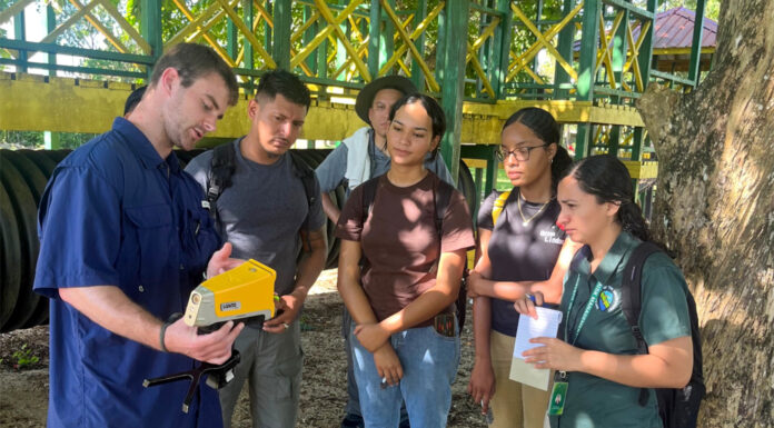 Mercer researchers develop faster, cheaper method to identify lead in paint a man points to a device while others look on