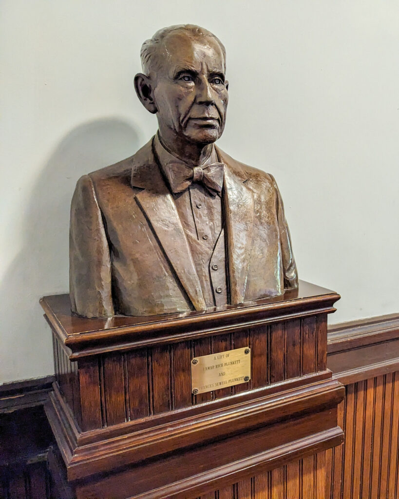 bust of a man sits on a pedestal 