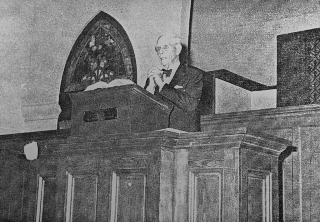 a black and white photo of a man preaching from a pulpit