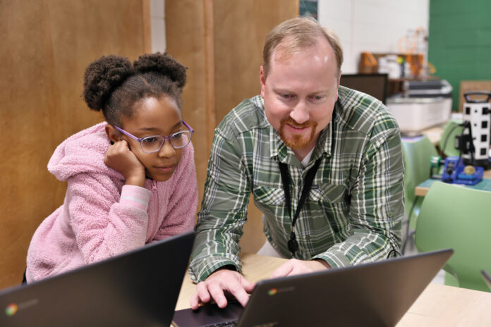 a man shows a young girl something on a computer