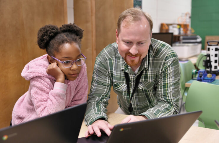 a man shows a young girl something on a computer