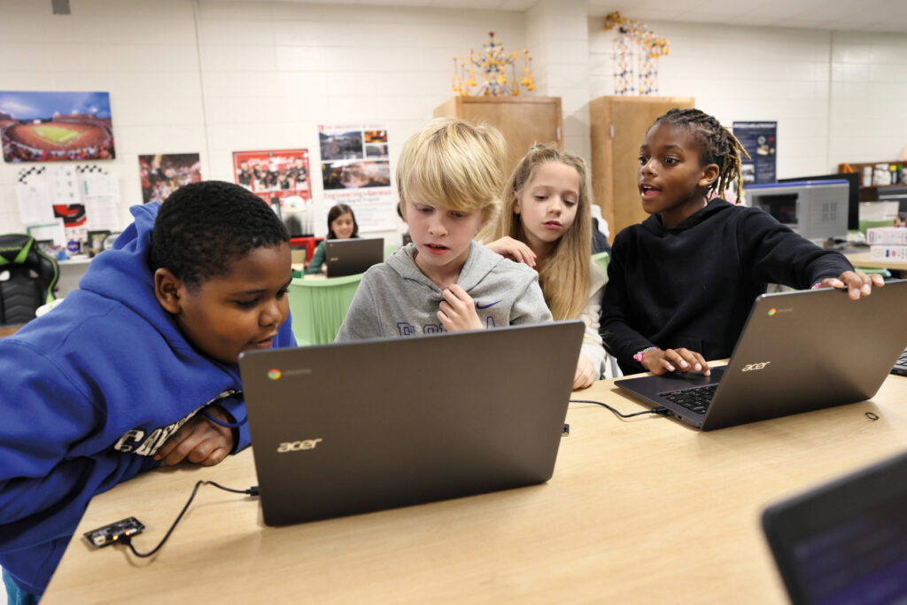 four children work on a computer