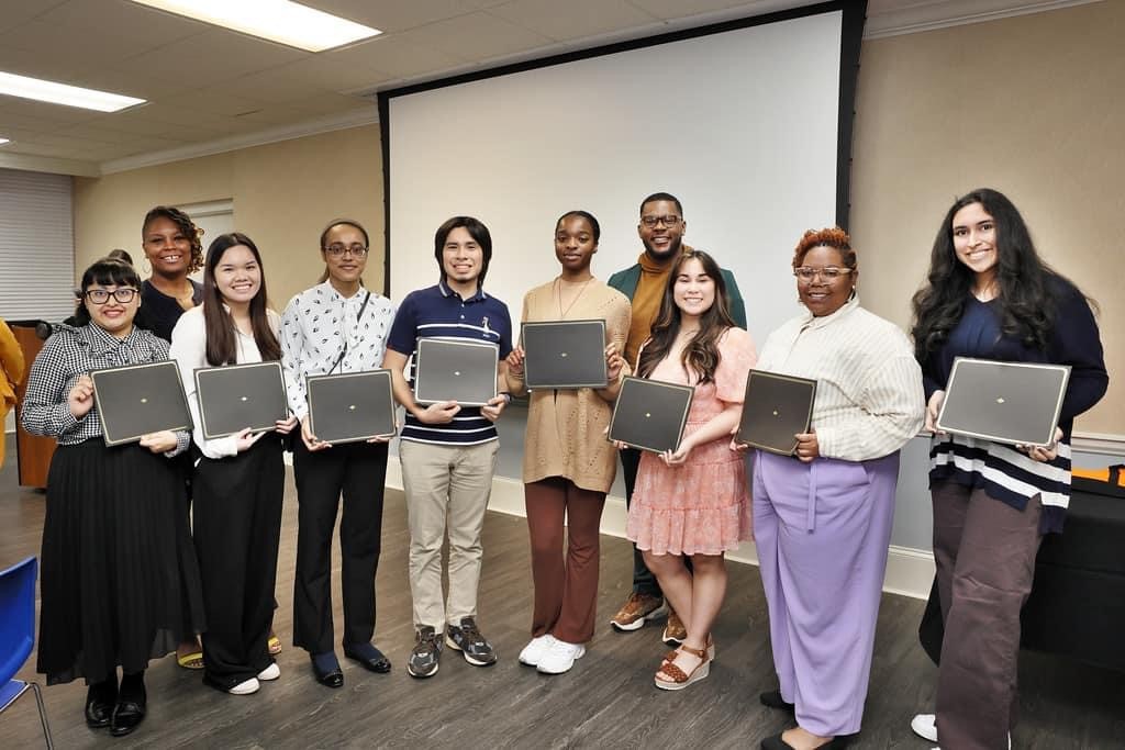 A group of college students stand holding awards, with the two African American Alumni Network co-chairs. 