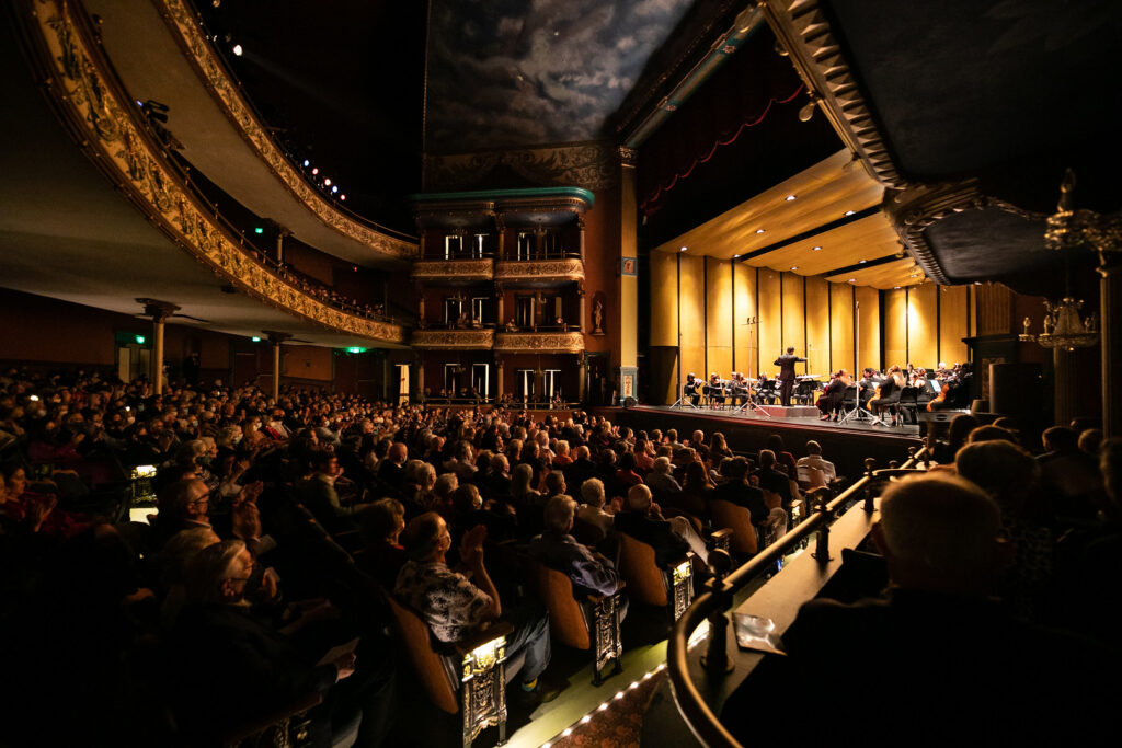 an audience listens to a symphony on stage