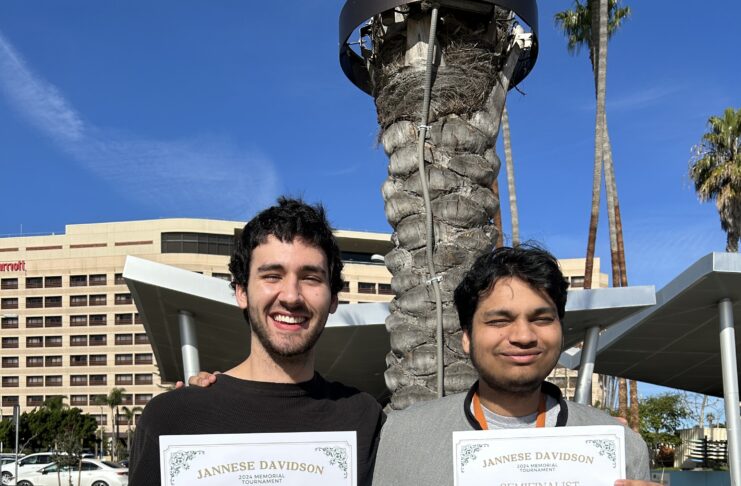 Two male college students holding winning debate certificates