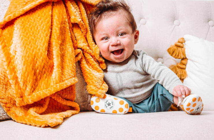 a baby sits in a chair and leans against an orange blanket