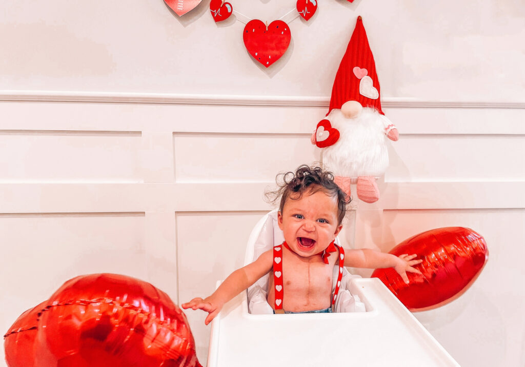 a baby in a high chair surrounded by heart decorations