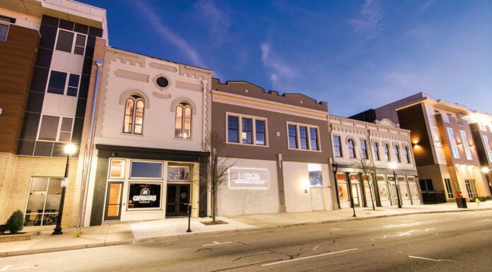 Capricorn to host special tour and Dickey Betts panel discussion on March 1 Street view of a row of modern and historic buildings with lit sidewalks and clear skies at dusk.