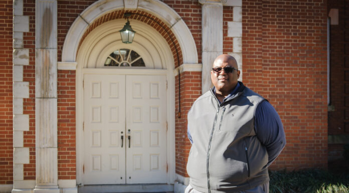Mercer Upward Bound graduate now mentors students, faculty as professor a man stands in front of a brick building