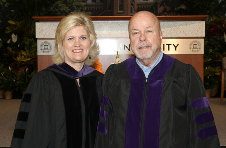 a man and woman stand next to each other in commencement attire