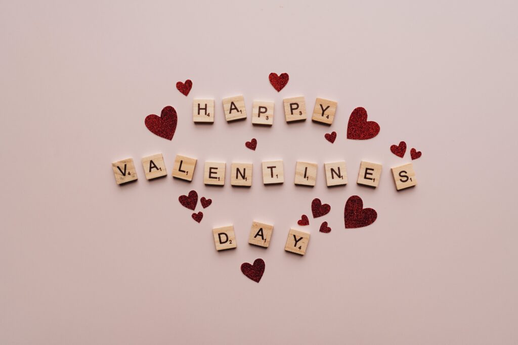 Scrabble tiles that spell Happy Valentine's Day, surrounded by red hearts.