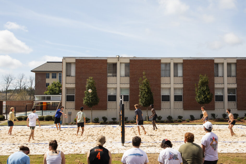 Several students play sand volleyball.