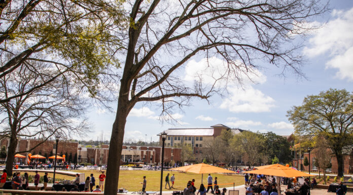 About 1,000 attend event to celebrate new College Street plaza Students gather on a green space with orange table umbrellas and trees.