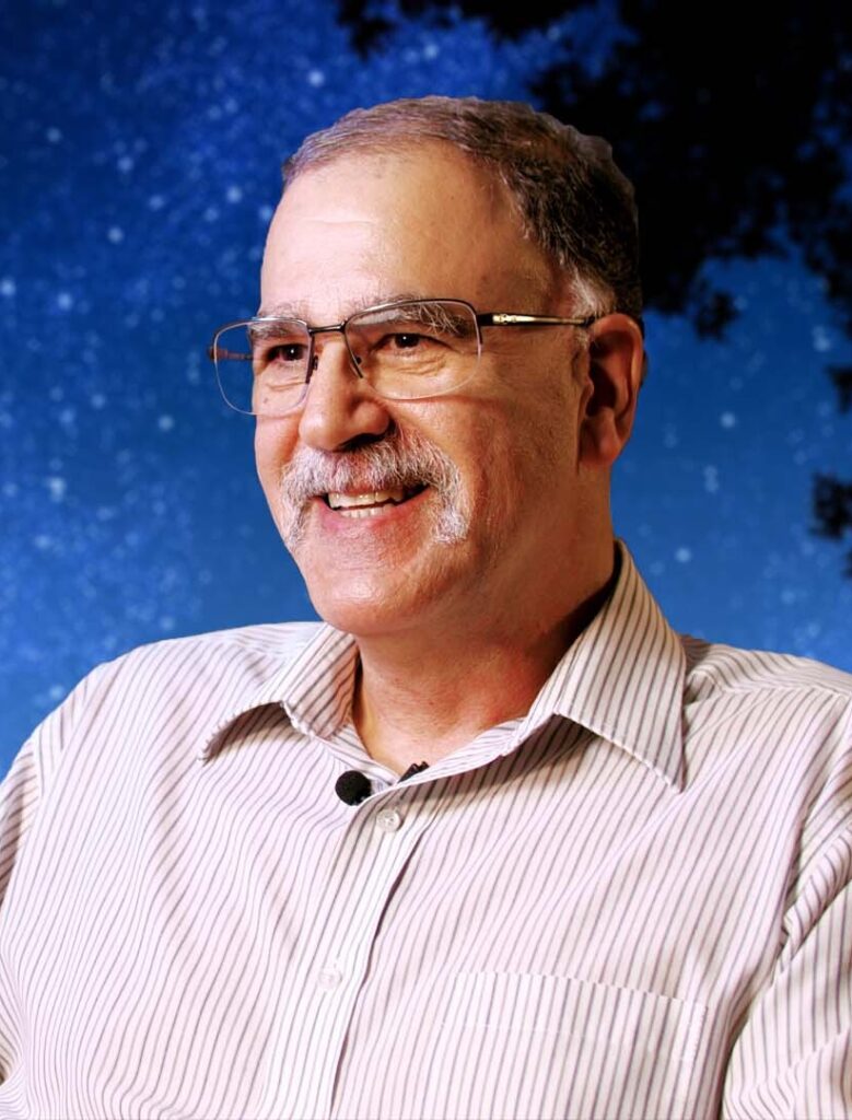 A headshot of a professor in a button-down shirt with stars in the background.