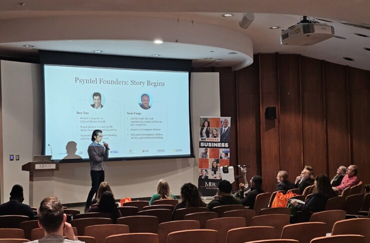 Benjamin Tan stands on stage in front of large projection screen presenting to audience. The screen says: Psyntel Founders: Story Begins, shows headshots of Ben Tan and Sam Fargo and provides some biographic information about each of them.