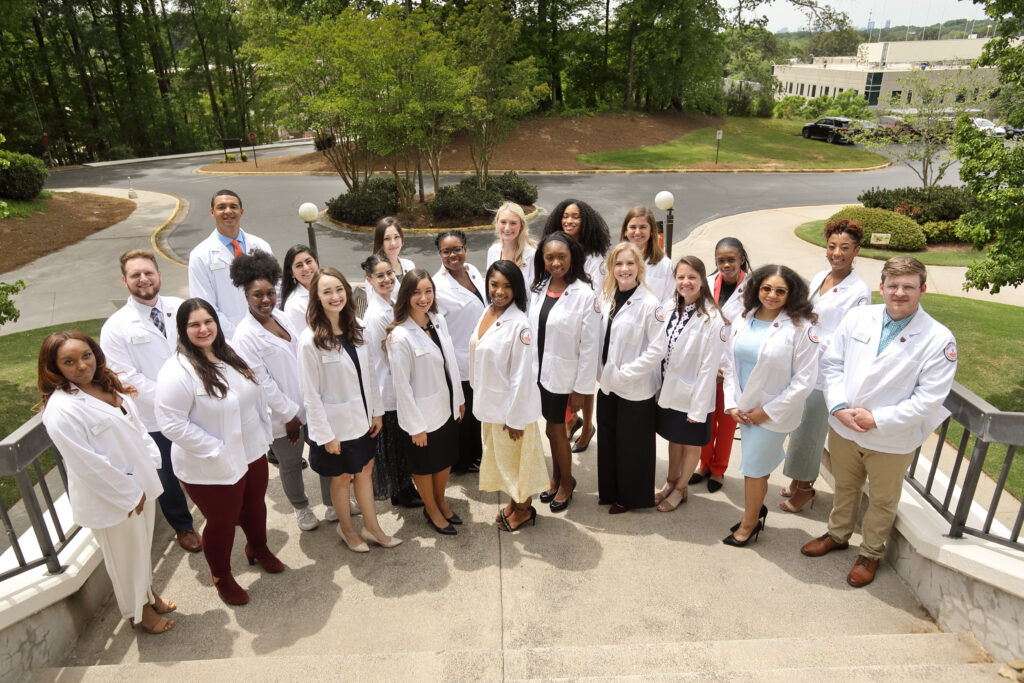 Group of PsyD students in white coats smiling