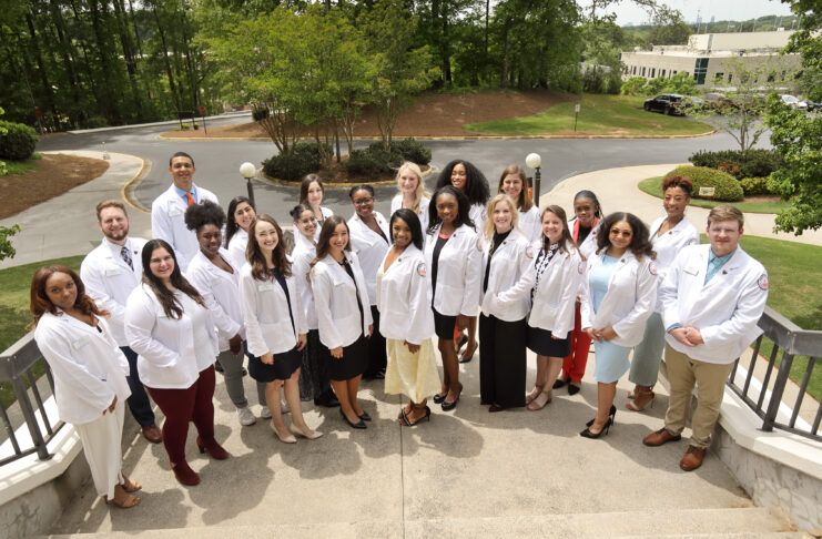 Group of PsyD students in white coats smiling