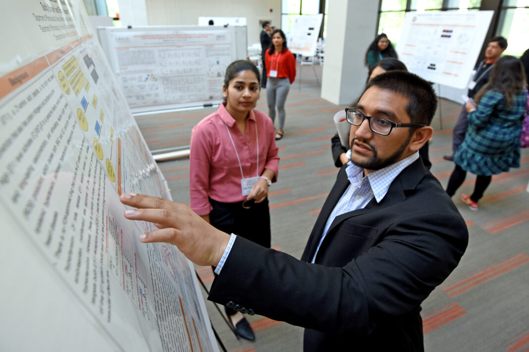man pointing at a whiteboard. Woman looking on.