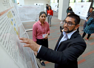 16th annual Atlanta Research Conference to showcase student, faculty scholarship Man pointing at a research poster. Woman looking on.