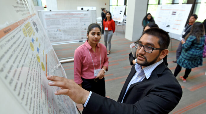 16th annual Atlanta Research Conference to showcase student, faculty scholarship Man pointing at a research poster. Woman looking on.