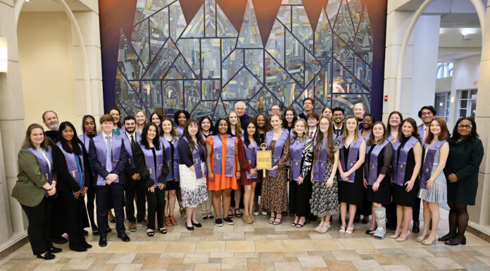 College of Liberal Arts and Sciences inducts 39 students into Phi Beta Kappa Society group of smiling faculty and students wearing Phi Beta Kappa sashes and holding plaque