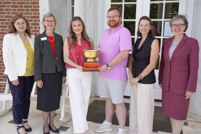 Mercer Law administration, Middle Georgia Food Bank administration, and two Mercer Law students stand on the law school's front porch holding the Law School Legal Food Frenzy Attorney General's Cup