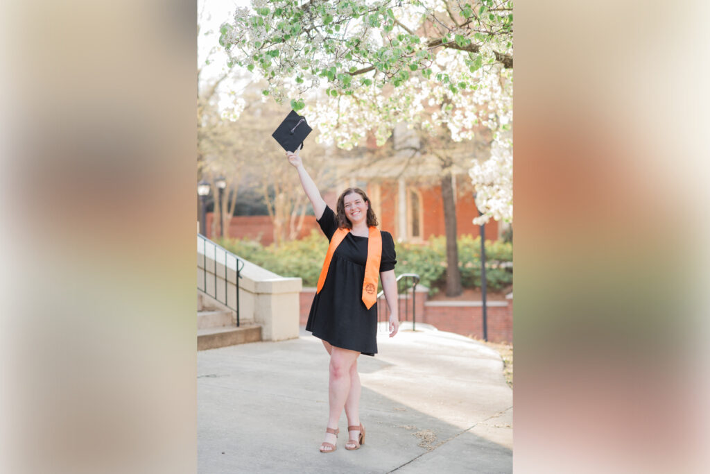 a student holds a graduation cap up in the air