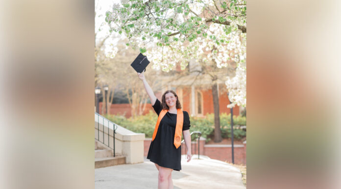 Graduate Spotlight: Caroline Ulsaker a student holds a graduation cap up in the air
