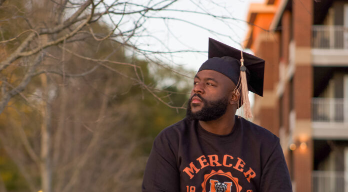 Graduate Spotlight: Demone Webb a man wearing a mercer sweatshirt and graduation cap looks off into the distance
