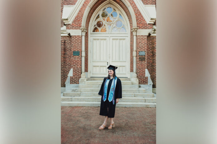 woman in graduate cap and gown standing in front of building