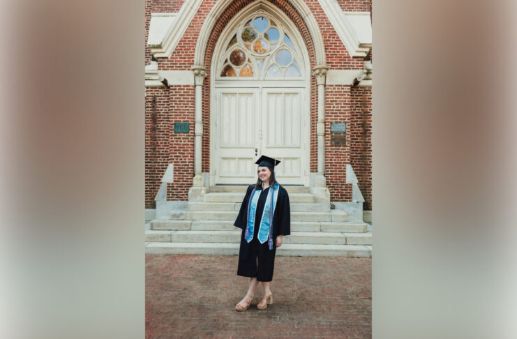 woman in graduate cap and gown standing in front of building