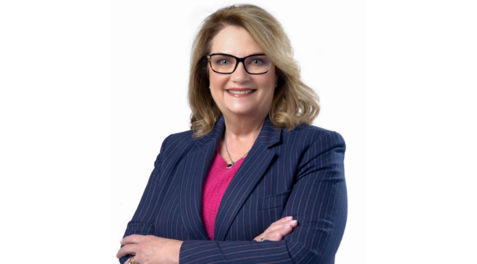 Mercer alumna works for biopharmaceutical company that ‘changes lives’ A professional woman with shoulder-length blonde hair and glasses is smiling at the camera. She is wearing a navy blue pinstripe blazer over a pink top and has her arms crossed.