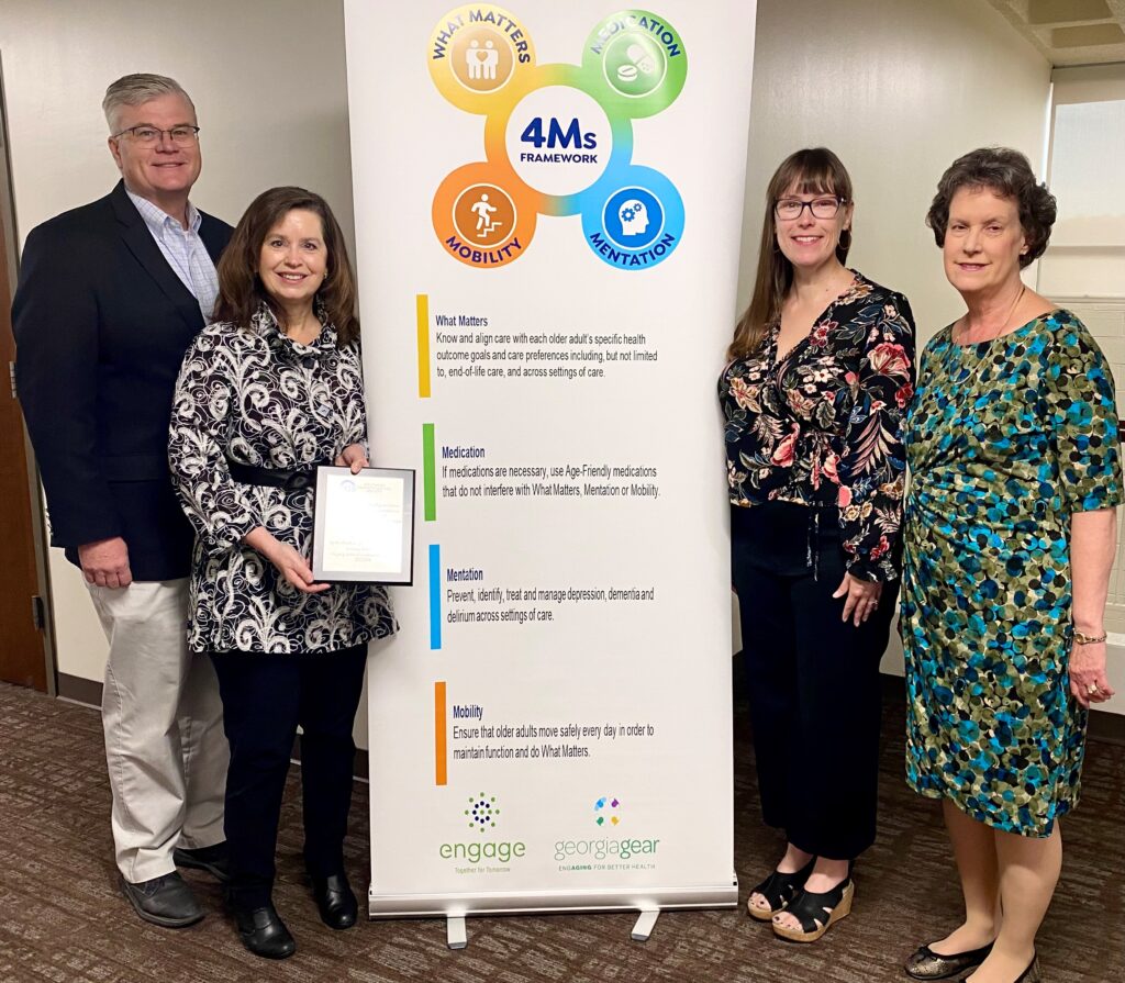 Four professors standing with award and banner