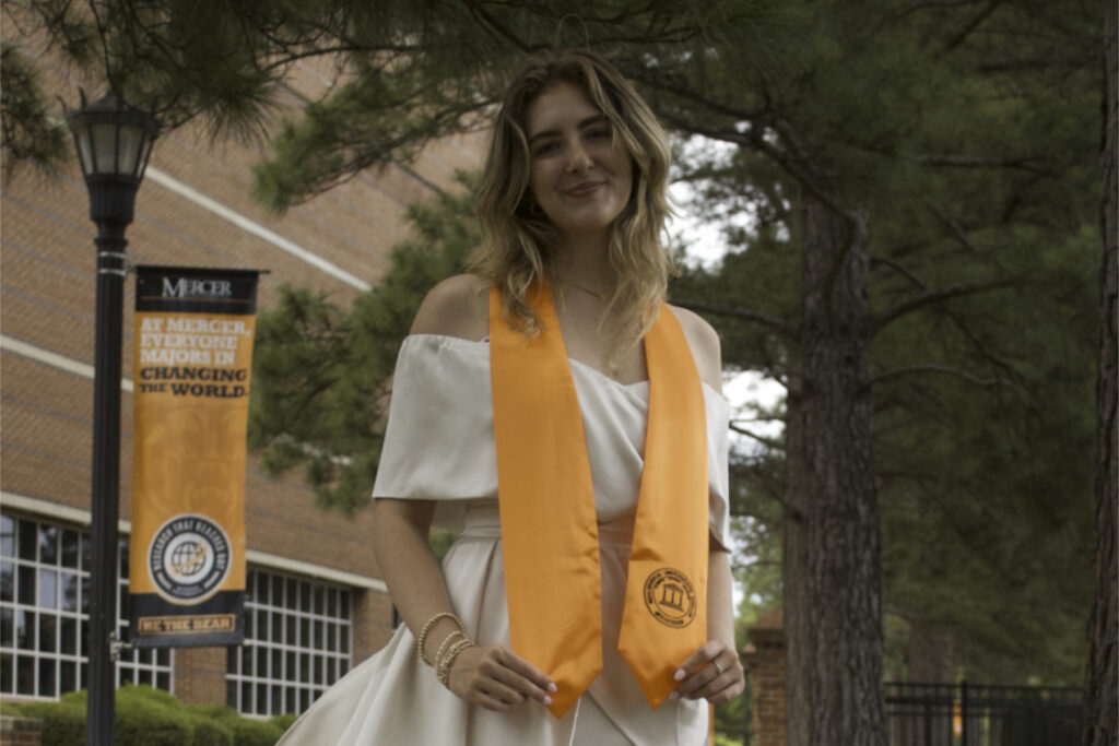 a woman in a white dress wears an orange stole around her neck