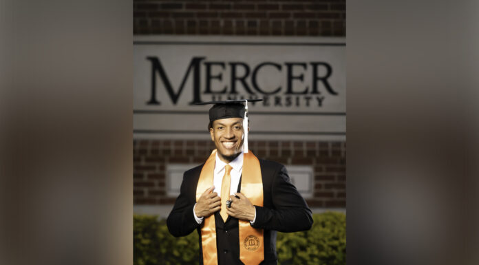 Graduate Spotlight: Chilton Tolliver man wears graduation regalia while standing in front of a mercer university sign