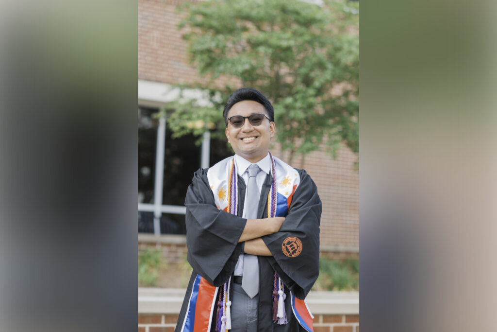 man wears graduation regalia and sunglasses