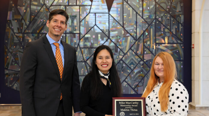 Engineering professor awarded 2024 Mike MacCarthy Mentorship Award Three people standing in front of a colorful stained-glass background. The woman in the middle is a holding a plaque that reads 'Mike MacCarthy Mentorship Award presented to Makhin Thitsa, April 16, 2024.'