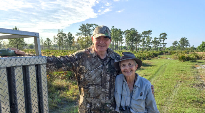 92-year-old Mercer alumna a noted doctor and turkey hunter A man and woman in hunting clothing and hats are shown in front of a grassy and tree-filled area.