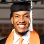 Headshot of Chilton Tolliver. He is wearing a black graduation cap and white button up shirt and orange tie under an open gown. He has an orange stole around his neck. 