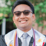 Headshot of Ervin Pangilinan. He is wearing a black graduation gown and a white button up shirt and gray tie can be seen underneath. He has a colorful stole and cords around his neck and is wearing sunglasses.