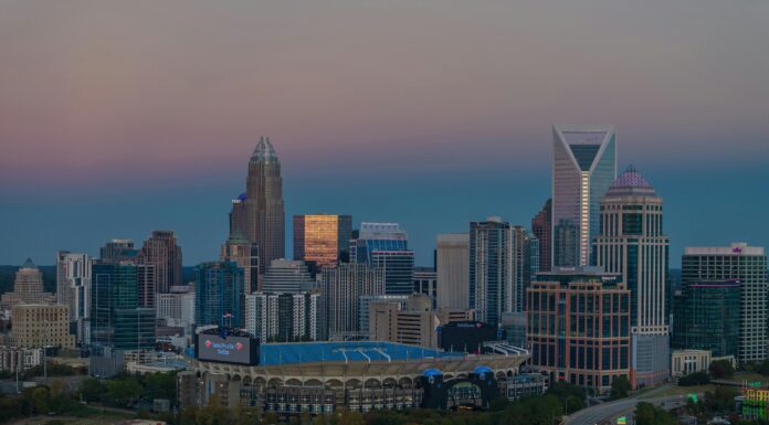 Students gain field experience during internships with prestigious corporations Dusk view of the Charlotte, North Carolina, skyline featuring modern skyscrapers with the Bank of America Stadium in the foreground and a highway leading into the city. The sky displays soft gradients from blue to pink.