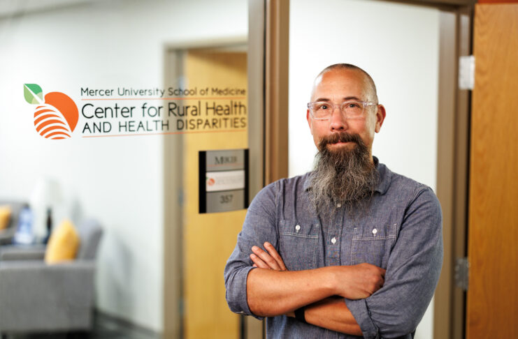 Michael Kramer standing confidently in front of the Mercer University School of Medicine, Center for Rural Health and Health Disparities.