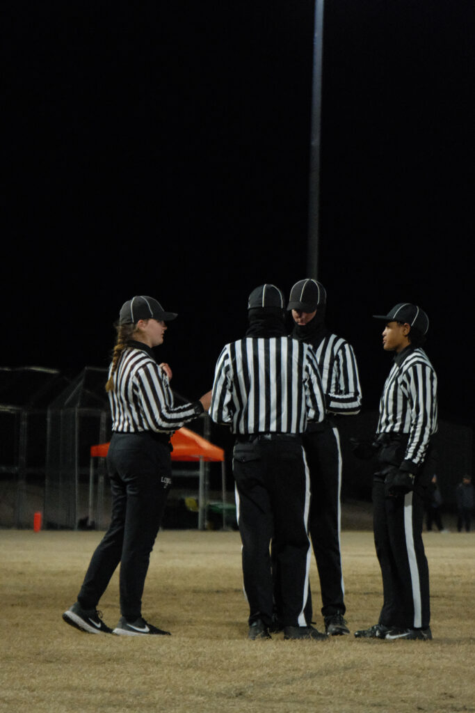 Four officials confer on a football field.