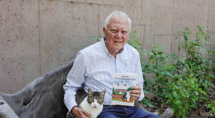 Former Georgia governor writes children’s book to honor late wife’s legacy Nathan Deal sits on a bench outside holding a book titled, "Veto, the Governor's Cat." A white and brown cat is seated next to him. Tomato plants are in the background.