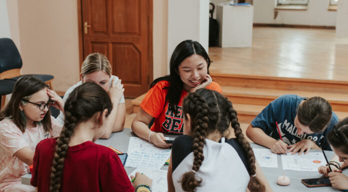 Finding hope among Ukrainian refugees in the Republic of Georgia A student wearing an orange Mercer T-shirt sits at a table with children writing on papers.