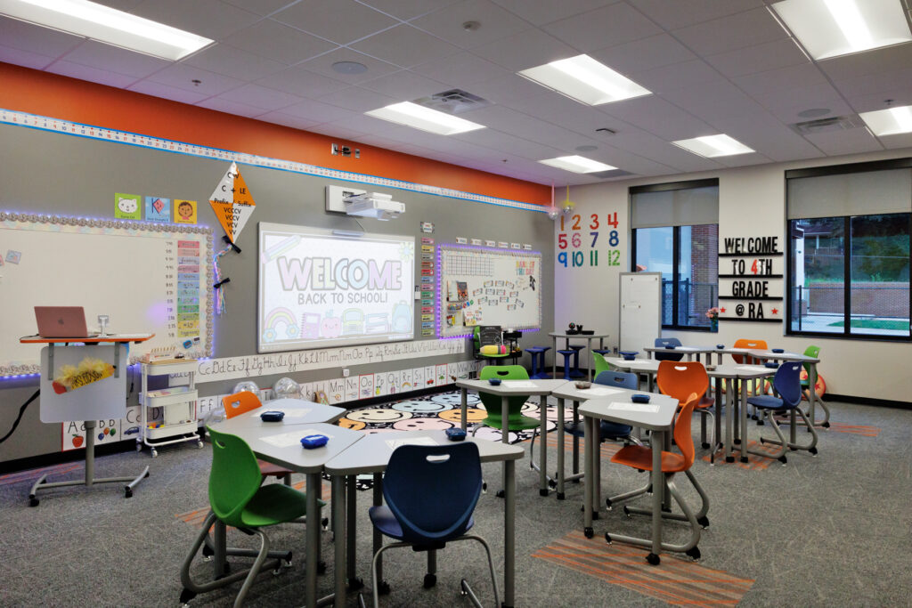 A brightly lit, modern classroom with brightly colored chairs and educational decorations.