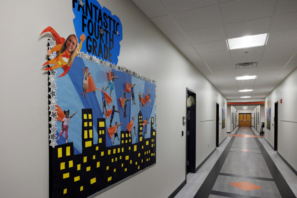 A school hallway features a display that says, "Fantastic Fourth Grade" and features a city skyline at night with children and their teachers dressed as superheros. 