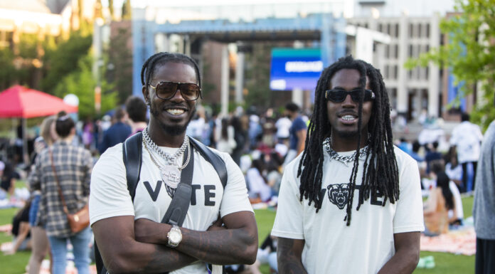 Mercer Votes aims to increase election participation as registration deadline nears Two college students wearing Vote T-shirts stand in front of an outdoor stage.