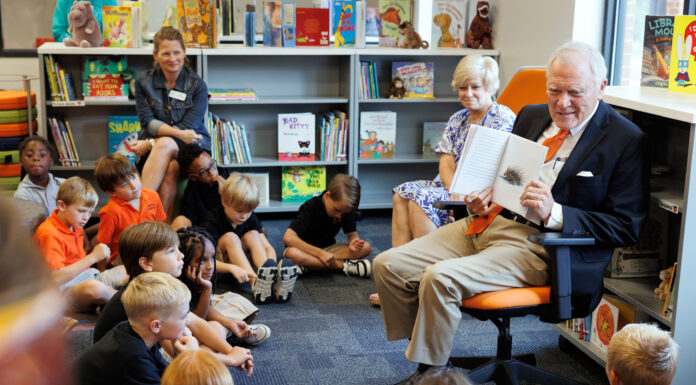 Former governor inspires Roberts Academy students with lessons of courage, literacy Former Georgia Gov. Nathan Deal, wearing an orange tie and navy blue blazer, shows a picture in a book to a group of attentive children inside a library.